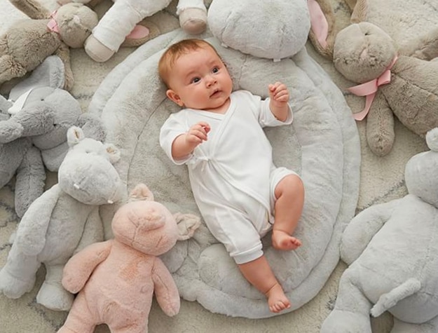baby lying among stuffed animals