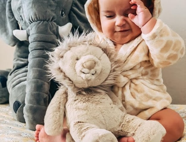 Baby with lion and elephant plush toys