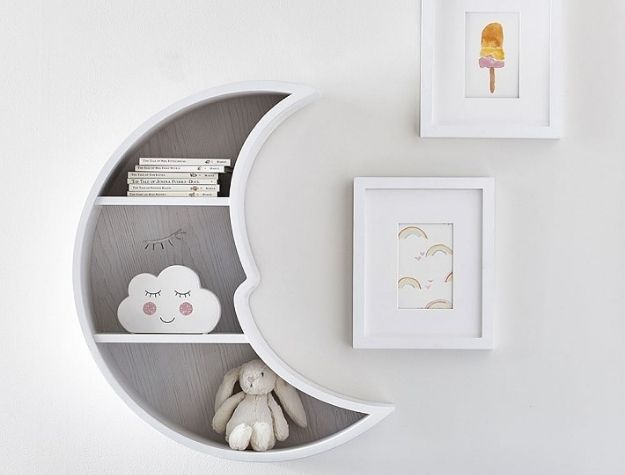 moon shaped shelf next to art prints