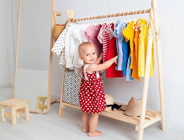Toddler looking at clothes on miniature clothing rack