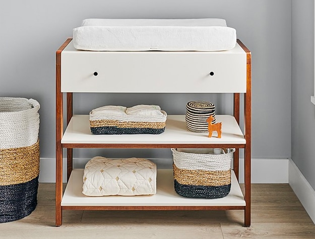 Modern wooden changing table with baskets and white shelves
