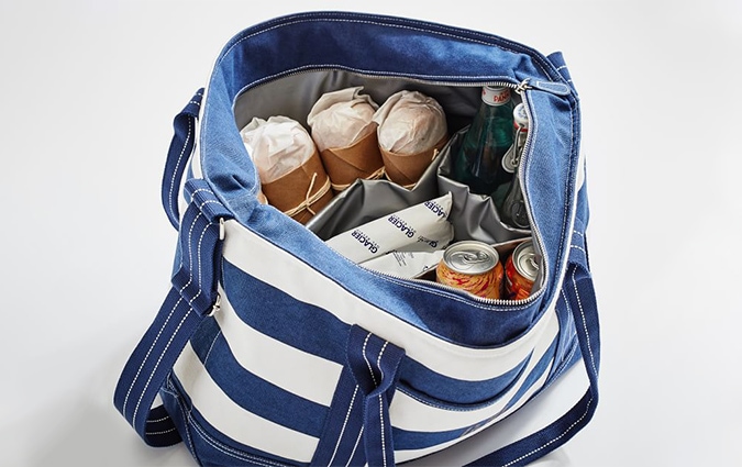 Blue and white cloth cooler with food and drinks inside 
