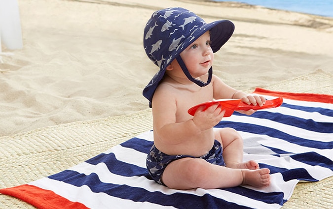 Baby playing at beach on striped towel