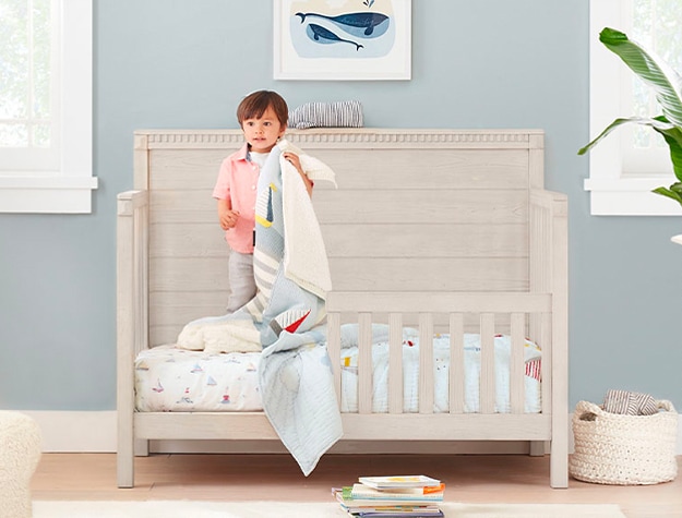 Toddler standing on tan wood bed