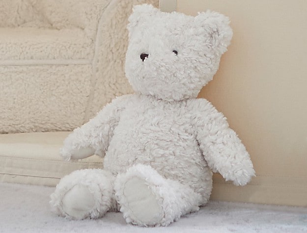 Peanut the St. Jude Bear, a white, plush teddy bear, sits upright against a plush children’s chair.