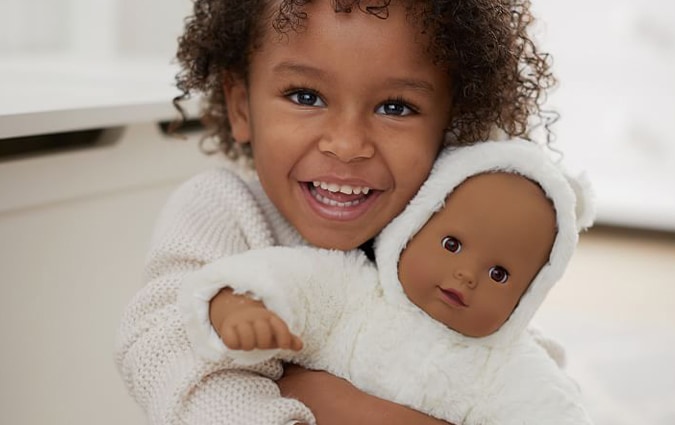 Young girl smiling holding baby doll