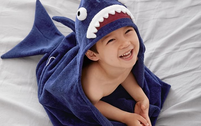 Young boy wearing blue shark towel