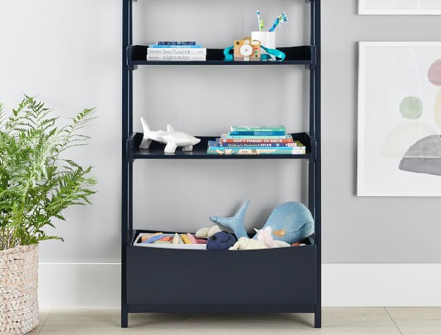 Navy blue angled bookcase near plant and wall art.