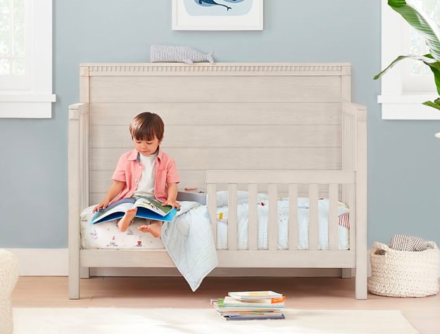 Toddler sitting on converted crib