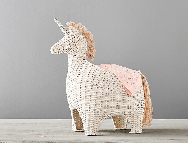Unicorn shaped wicker basket with blanket in it. 