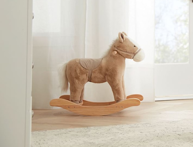 Brown rocking horse in front of white curtains