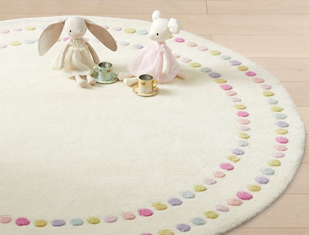 Cream and polka dot round rug with plush bunny and mouse toys sitting on it