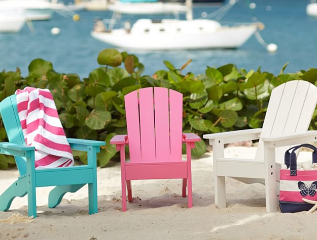 Turquoise pink and white wooden chairs in front of a beach scene