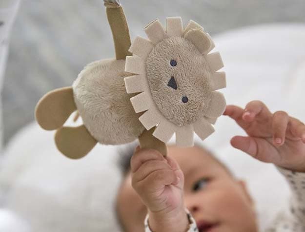 A baby playing with a Skip Hop X PBK Dreamy Skies activity gym