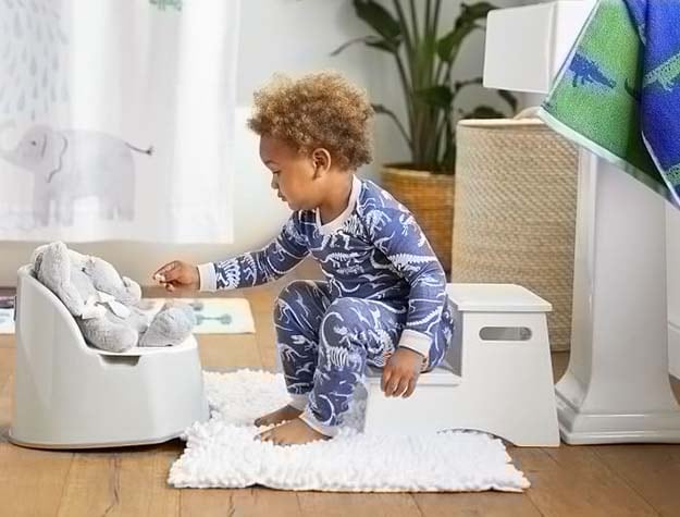 A child in pajamas sitting on a classic step stool in a bathroom