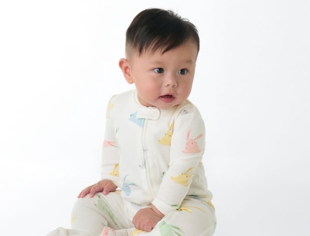 Baby wearing white pajamas decorated with colorful bunnies