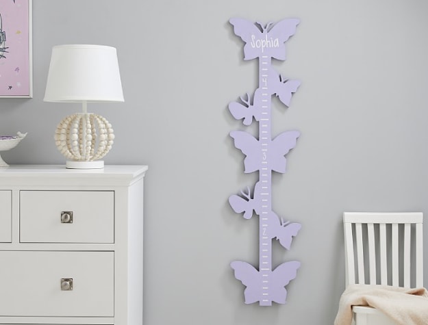 purple butterfly-themed growth chart in bedroom next to chair and dresser