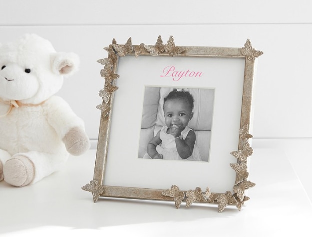 silver square frame adorned with butterflies with photo of baby labeled with the name “Payton” next to plush lamb