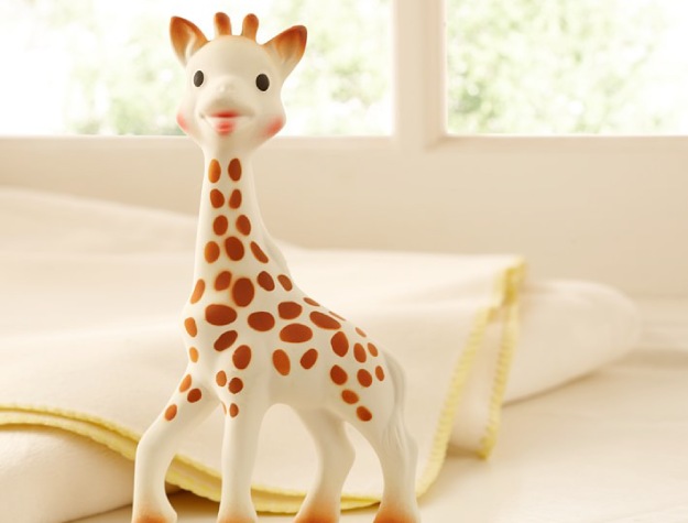 smiling giraffe toy placed in front of cream-colored blanket
