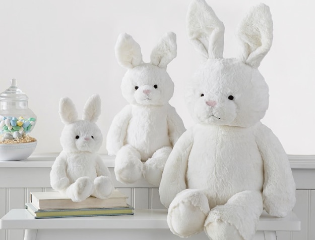 three plush bunnies of various sizes on bench and countertop