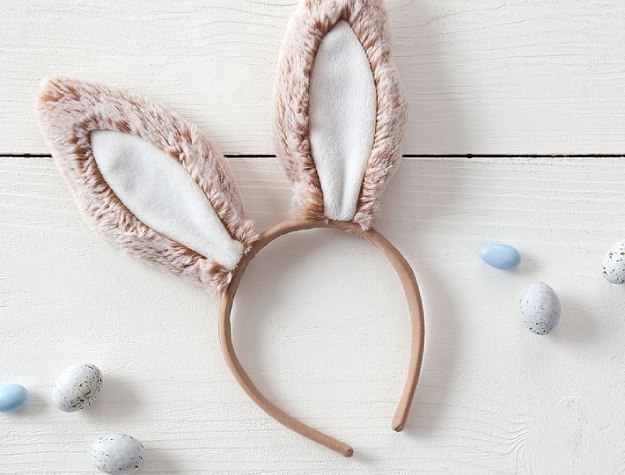 fuzzy wearable bunny ears on wooden surface next to small colorful eggs