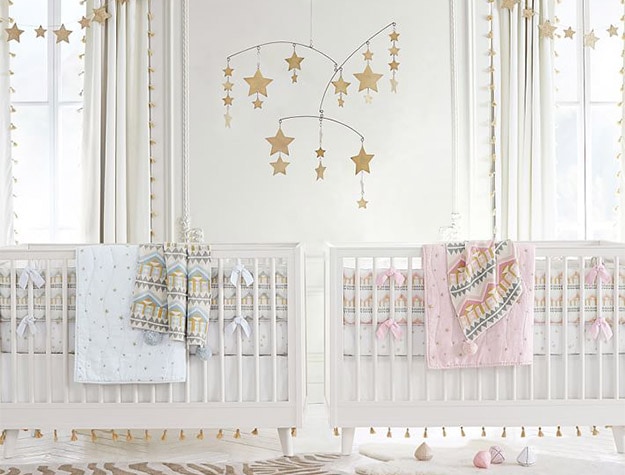 The Emily & Meritt Star Ceiling Mobile hanging above cribs.