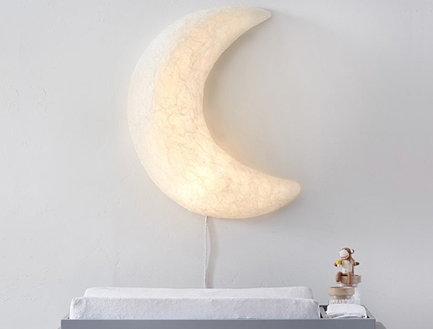 Paper mache light up moon lamp above changing table.