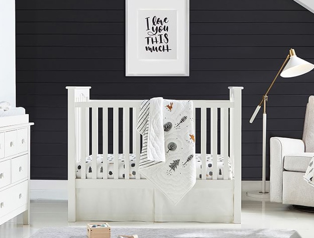 Kendall convertible crib in front of black wall with framed art.