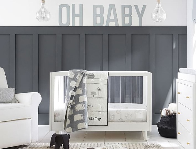 Sloan acrylic convertible crib with “Oh Baby” letter art and sheep throw blankets.