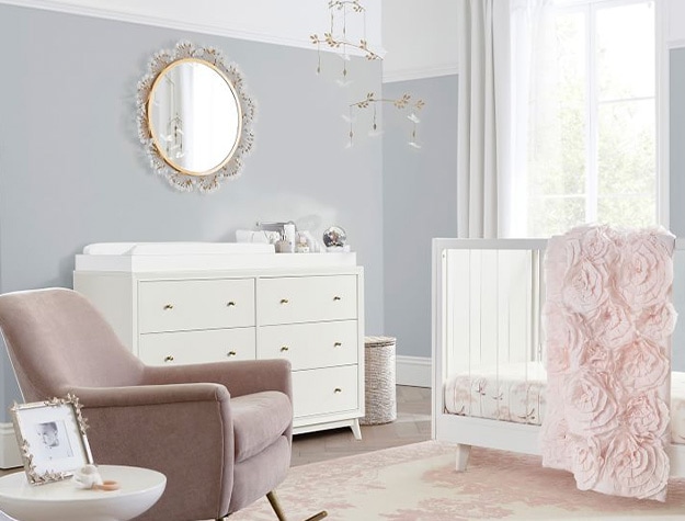 Monique lhuillier floral spray mirror above changing table with blush rocker to the side and white crib.