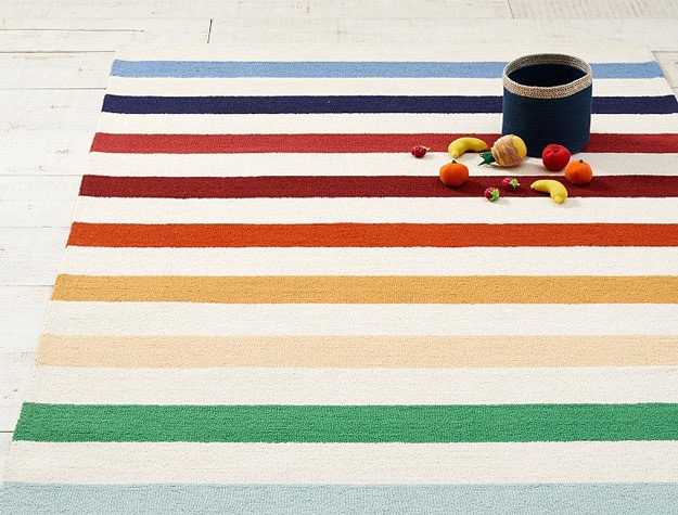 Rainbow stripe kids rug with fruit toys and basket.