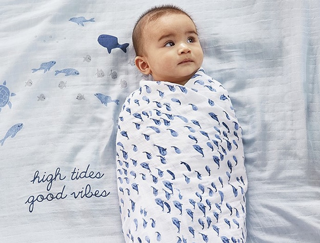 Baby wrapped in jack nautical organic muslin baby swaddle.