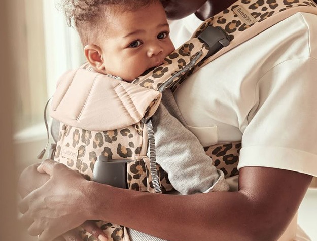 Parent holding baby in a BABYBJÖRN Baby Carrier One with cheetah print.