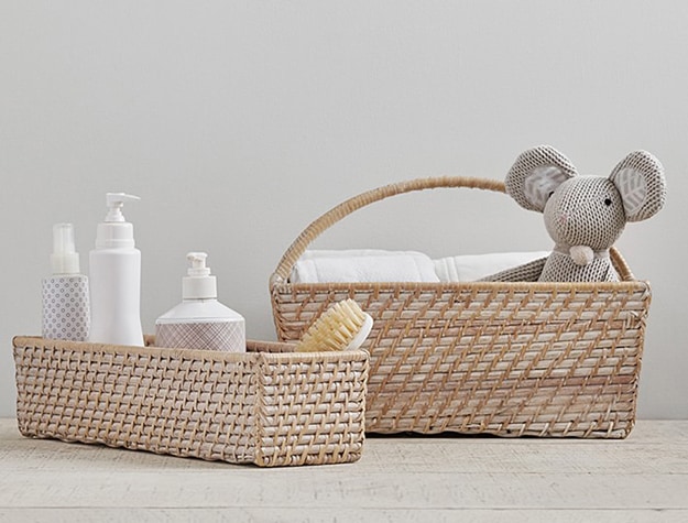 Two Quinn Nursery Storage baskets with bath products, towels and a stuffed animal.