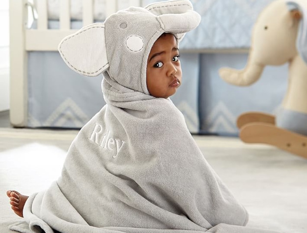 Child wearing Elephant Hooded Baby Towel personalized to read Riley on the back.