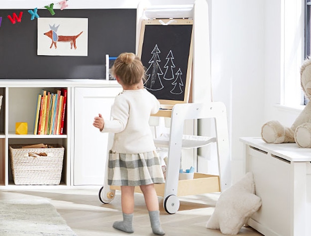 Kid playing with chalkboard easel in a daycare.