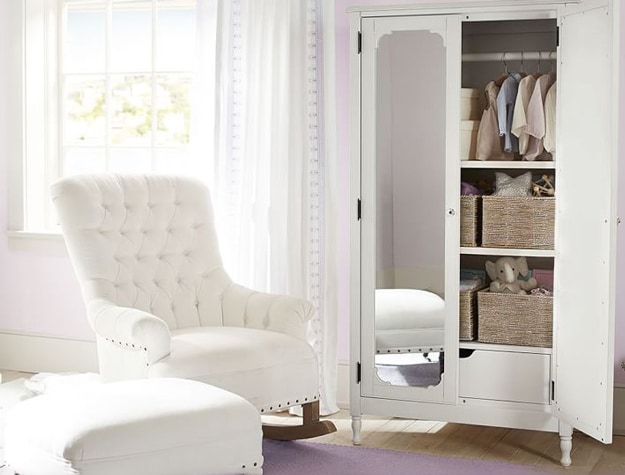 White armoire with mirrored door next to a rocking chair.