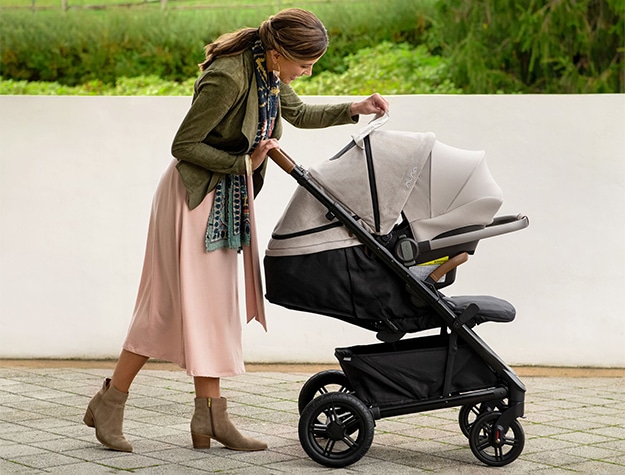 A woman checks on an infant in the Nuna Tavo Next + PIPA RX Travel System.