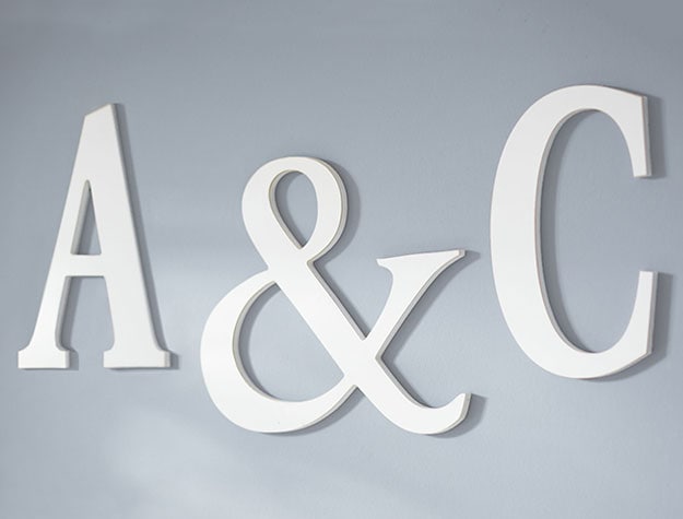 White hand-painted decorative letters hung on a gray wall.