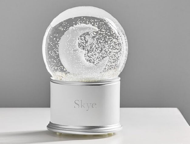 A crisp white slow globe with a crescent moon sits atop a table.
