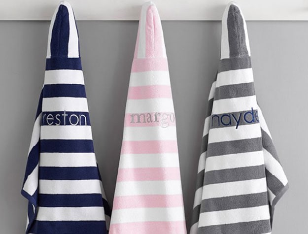 Three rugby-striped hooded towels hanging on wooden dowels.