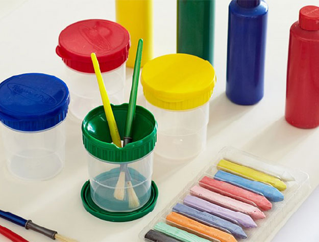 Colorful art easel accessories including pastels, paint brushes, and containers of paint.