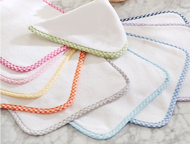 Ten washcloths with colorful gingham edges fanned out on a countertop.