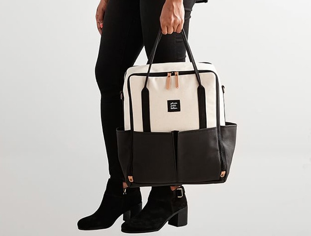 An adult dressed in black holds a black and white bag.
