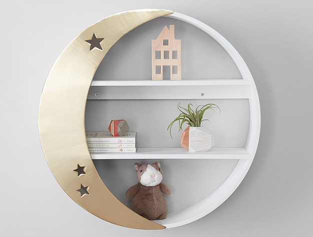 Circular shelving unit with gold crescent moon displaying books, toys and decor.