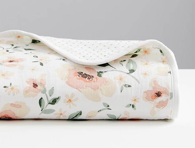 Floral print muslin blanket folded to show dotted print on opposite side.