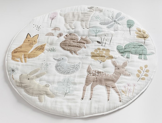 Play mat decorated with cartoon animals, flowers and branches.