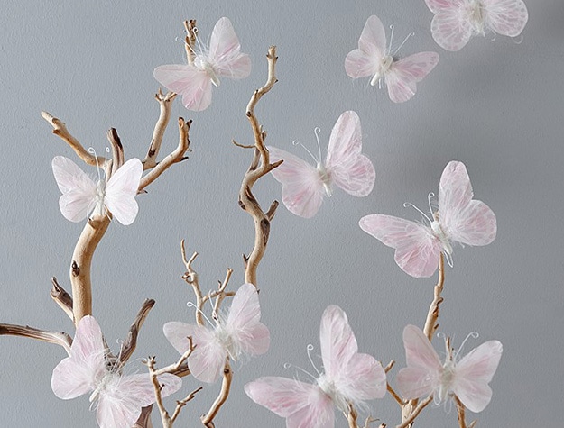 Tree branch decor with pink butterflies attached to branches and wall.