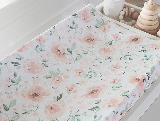 Floral-print changing pad with a compartment containing wooden toys.