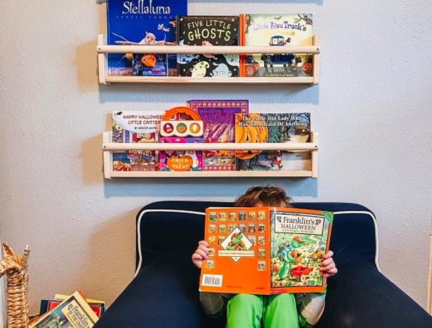 Child reading beneath wall shelves with books